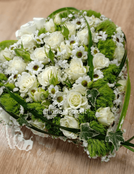 Composizione a forma di cuore con rose e altri fiori di colori assortiti.